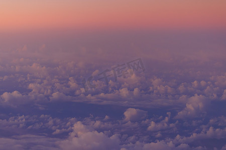 紫色的光芒摄影照片_日出时，云层和蓝色海洋上空地平线上的粉红色光芒