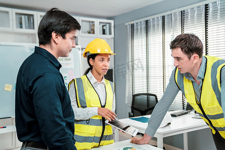 工程师和称职的雇主在办公室与平板电脑一起讨论。