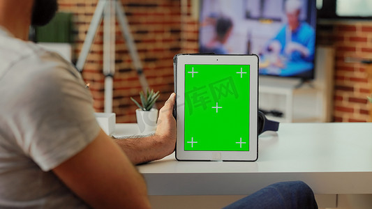 男性自由职业者在家中分析现代平板电脑上的绿屏
