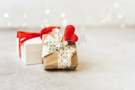 有红色弓和心脏形状的礼物或礼物盒在光背景。