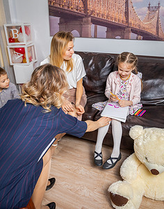 心理治疗摄影照片_一位女心理学家在家庭招待会上与孩子交流。