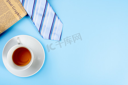 父亲节快乐背景概念，蓝色领带、报纸和蓝色背景的茶杯，带有文本复制空间。