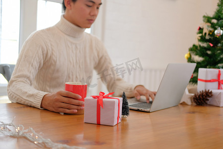 男人拿着咖啡杯 & 在圣诞节期间在家里使用电脑。
