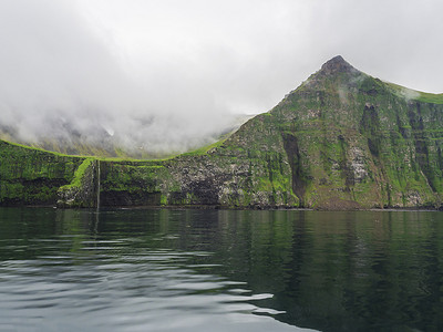 陡峭的绿色 Hornbjarg 悬崖和瀑布，欧洲最大的鸟悬崖，西峡湾，冰岛偏远的 Hornstrandir 自然保护区，迷雾海洋和喜怒无常的天空