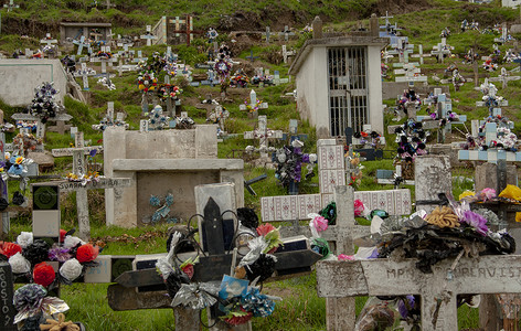 为了纪念亲人：一张拉丁美洲墓地的照片，山上有插花和石头十字架