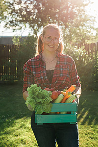 女农民提着一盒采摘的蔬菜-花园和收获农产品进行网上销售。