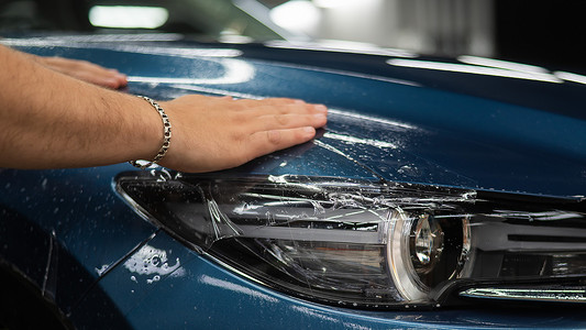 防护汽车摄影照片_汽车服务中的师傅给车身贴上防护装甲膜。
