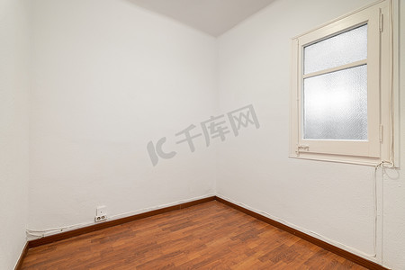 空荡荡的房间，铺有复合地板，新粉刷成白色的墙壁，明亮的窗户配有磨砂玻璃。