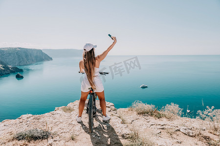 一位骑山地自行车的女自行车手，眺望山海风光。
