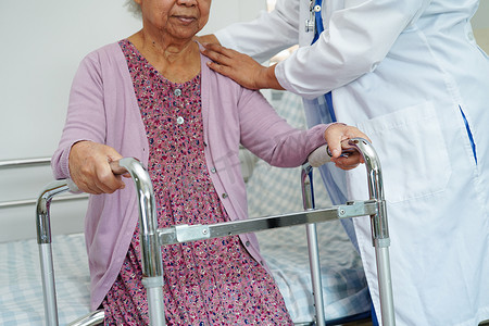 医生帮助亚洲老年妇女残疾患者在护理医院与助行器一起行走，医疗理念。