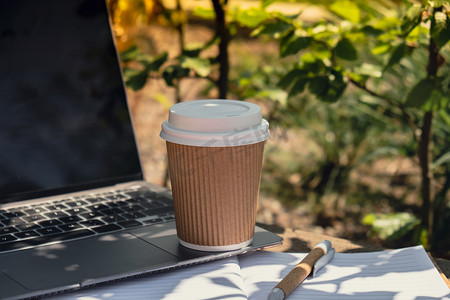 用纸质笔记本和笔记本电脑在工艺回收纸杯中带走咖啡。