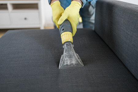 男士干洗店员工用专业提取方法将防护橡胶手套清洁沙发。