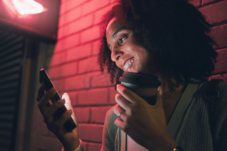 夜晚咖啡摄影照片_黑人女性、智能手机和带微笑的咖啡杯、夜晚和社交媒体，用于聊天、在线浏览和城市户外活动。