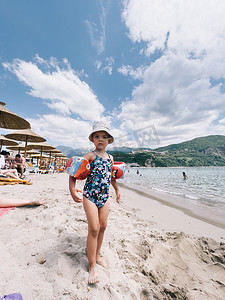 充气臂章的小女孩站在沙滩上