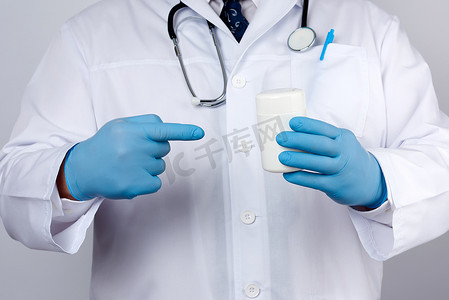 一件白色医疗外套和蓝色乳汁手套的医生拿着whi
