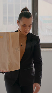 爬楼梯女摄影照片_在初创公司办公室爬楼梯的女商人拿着外卖食品餐袋