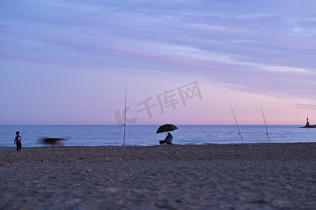 宁静的场景摄影照片_蓝色秋日夕阳下，海滩上水平宁静的场景，渔夫剪影