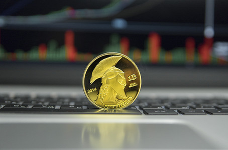 笔记本电脑银键盘上的金泰坦比特币硬币和屏幕上的图表图表作为背景。