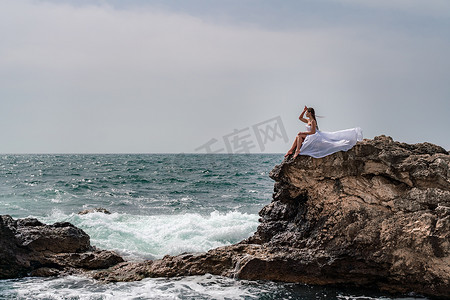 暴风雨中的女人坐在海中的一块石头上。