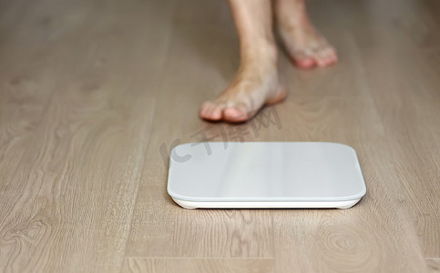 测量体重摄影照片_在体重秤上行走的人测量体重。