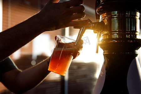 英国聚会摄影照片_将啤酒倒入塑料杯中。