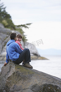 坐在海边岩石上的情侣