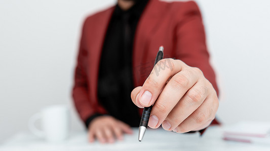 穿着红色西装的男模特坐在白桌旁，用笔指着重要信息。