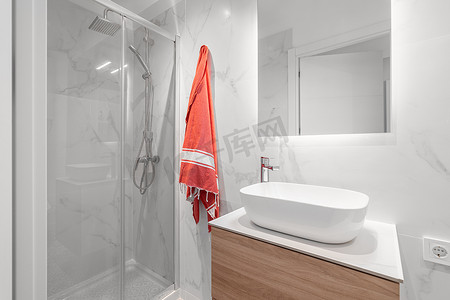 白色紧凑型浴室配有带镜子的水槽和玻璃淋浴间，经过时尚装修。