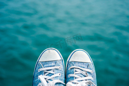 蓝色海洋图案摄影照片_运动鞋上模糊蓝色海洋与散景。
