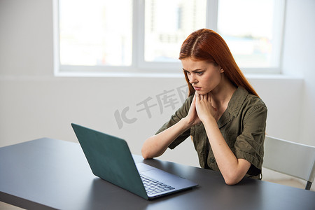 全职摄影照片_办公室里一位红发女性若有所思地坐在笔记本电脑前的肖像
