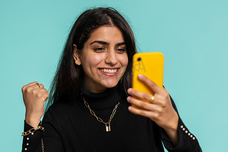 快乐兴奋的印度赢家女人用智能手机说哇，是的，发现了伟大的中奖好消息彩票