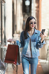 低价抢购限时促销摄影照片_亚洲时尚女性提着购物袋在购物中心散步，同时进行限时促销
