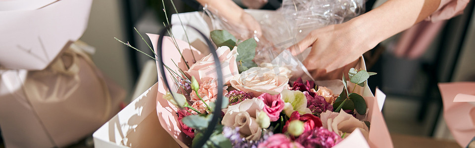 花店人摄影照片_专业卖花人的年轻女人正在花店做花束