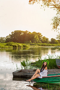 头戴花环的年轻女子，日落时分在河上的船上放松。