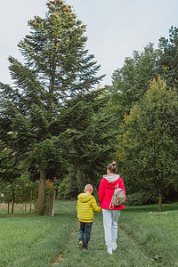 美丽的家庭-妈妈带着小儿子在秋天阳光明媚的大自然中散步。
