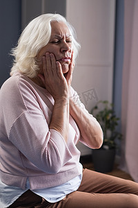 女人因牙痛而用手触摸嘴巴，表情痛苦