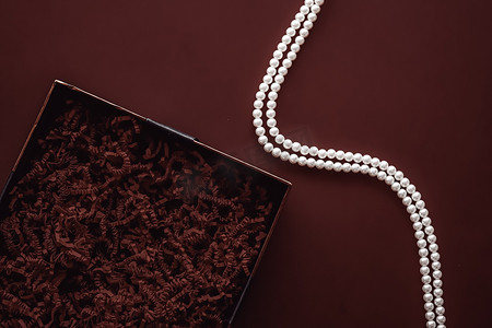 节日礼物、珍珠首饰项链和豪华礼物的美容盒订阅包模型，巧克力背景上空空的开放礼盒平铺作为在线购物交付，平铺