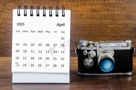 桌子相机摄影照片_2023 年 4 月的月度台历，供组织者在桌子背景下用老式相机计划 2023 年。