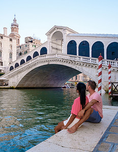 一对男女在威尼斯 Ital 的城市旅行中坐在里亚托桥的海滨