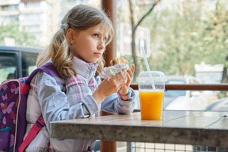 户外肖像漂亮女学生 8、9 岁，带芝士汉堡和橙汁
