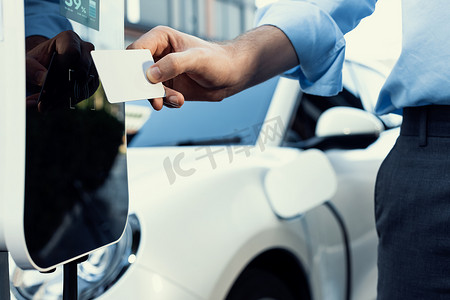 手持信用卡并支付充电站到进步的 EV 汽车。