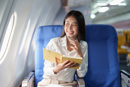 亚洲商务女性乘客坐在商务舱豪华飞机上，同时使用笔记本书工作，同时旅行概念