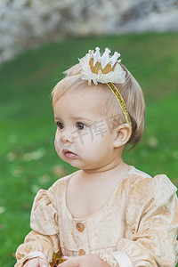 万圣节城堡摄影照片_日落时分，穿着公主服的迷人婴儿在城堡附近散步