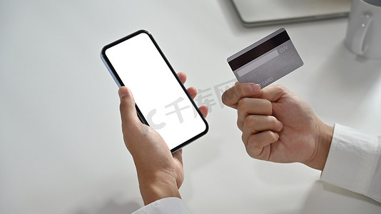 手持信用卡并使用智能手机进行网上购物、电子商务或网上银行业务
