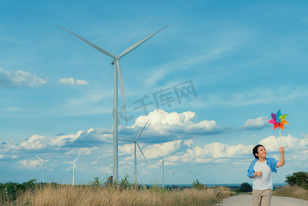 进步的摄影照片_进步的年轻亚洲男孩在风力涡轮机农场玩风车玩具。