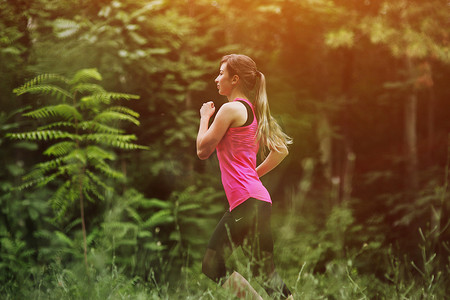 跑步在早晨森林步道的年轻健身妇女。