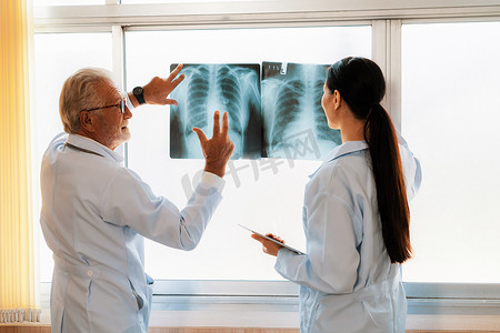 无菌室摄影照片_两名医生在无菌室检查 X 光片以进行医学 X 光诊断。
