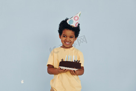 快乐的非洲裔美国小孩在生日聚会上在室内玩得开心拿着蛋糕