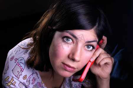 黑头发绿眼睛的可爱年轻女人用红色手机壳打电话