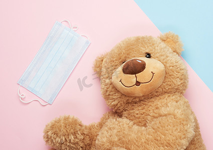 蓝色粉色背景中的大泰迪熊和医用口罩